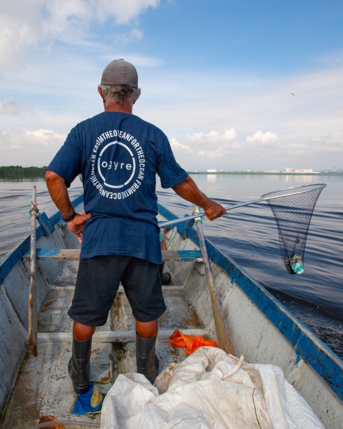 Man on a boat collecting plastic with a net for Ogyre