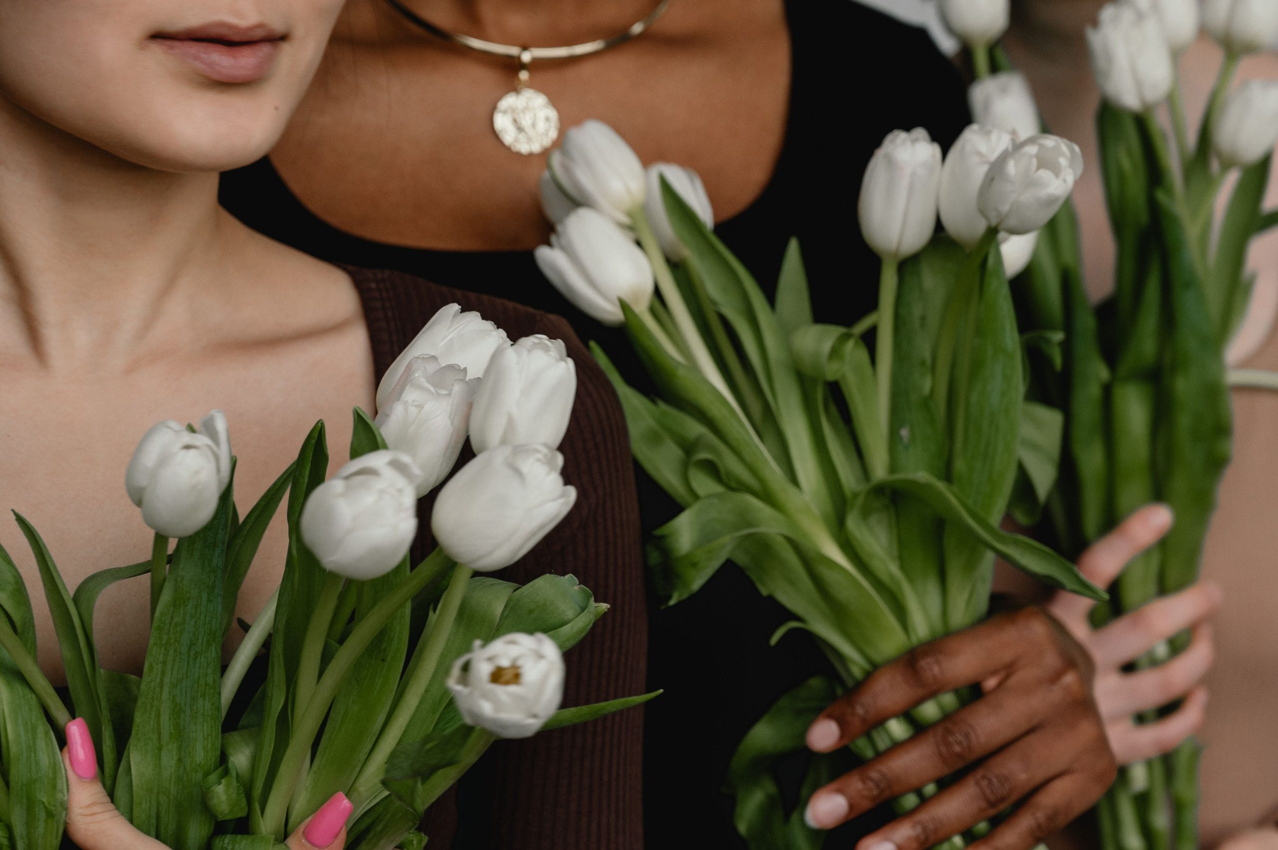 three women holding white tulips