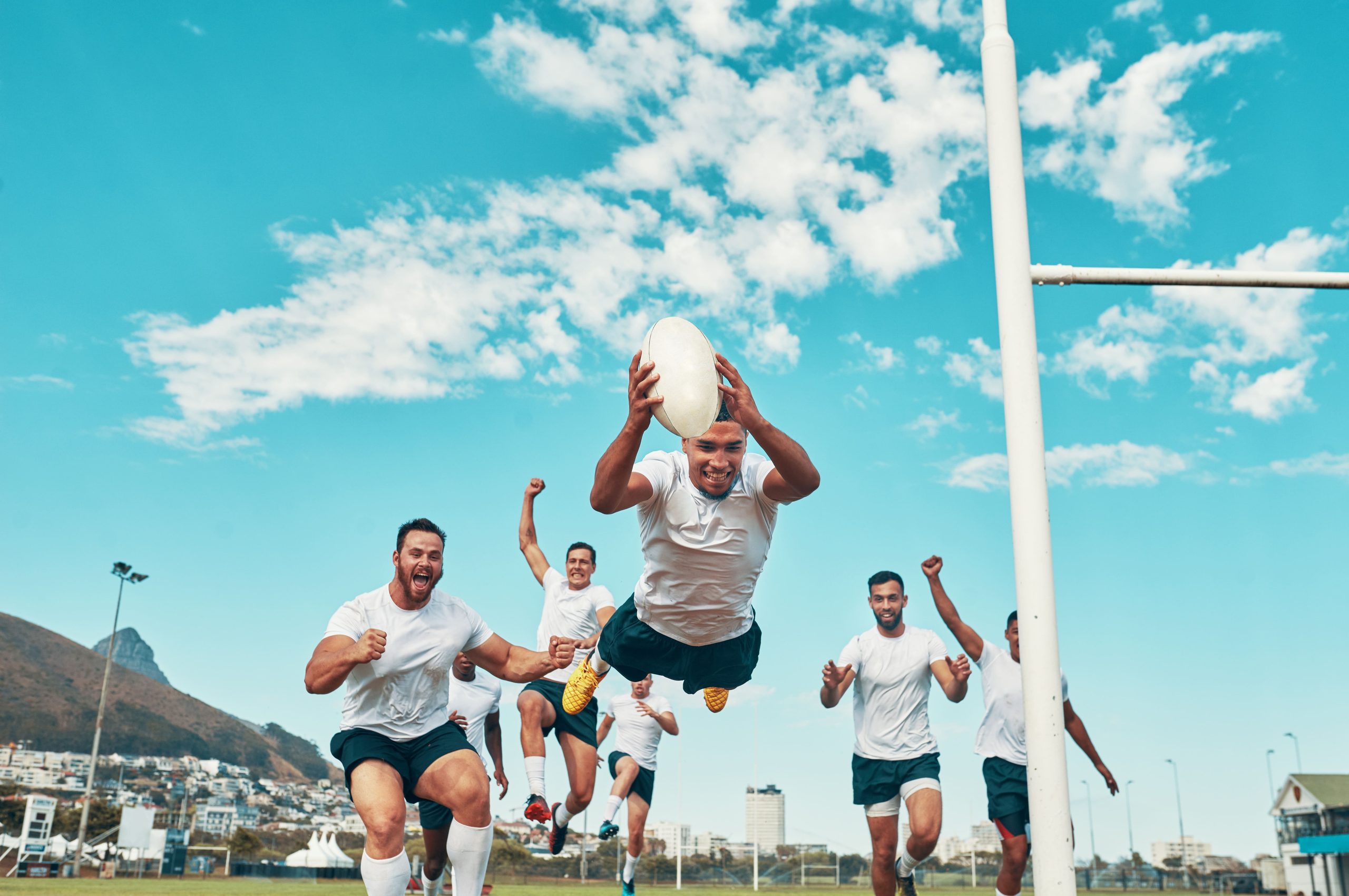 Guys in white jerseys running towards the end zone on an American football field