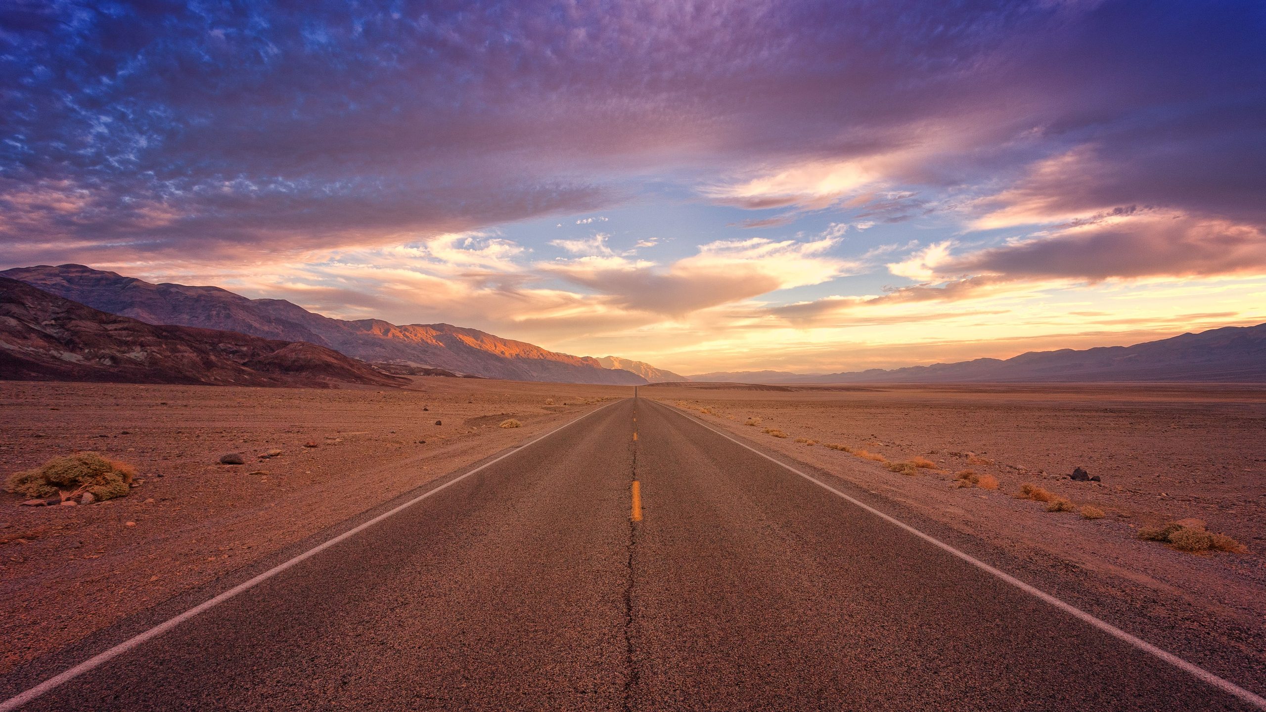 Deserted road ahead with mountains in the background